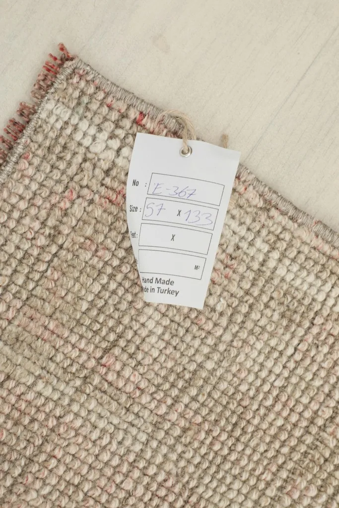 Close-up of the rug's label showing the dimensions 57 x 133 cm and origin, alongside the wool pile.