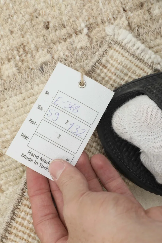 Hand holding the product tag displaying the rug's dimensions and origin