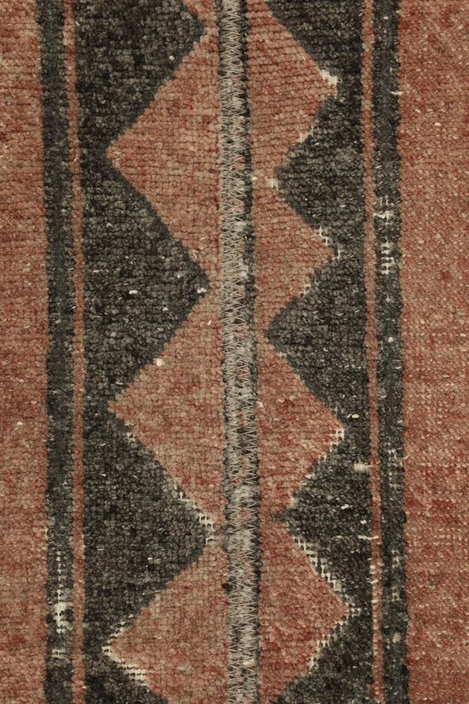 Detailed view of the central black and rust geometric pattern, showing the wool pile texture.