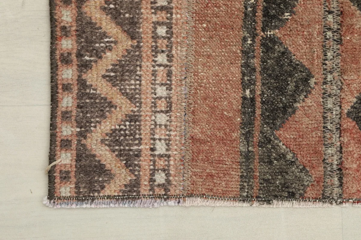Corner detail of the rug, showing the zigzag border design and the short fringe.