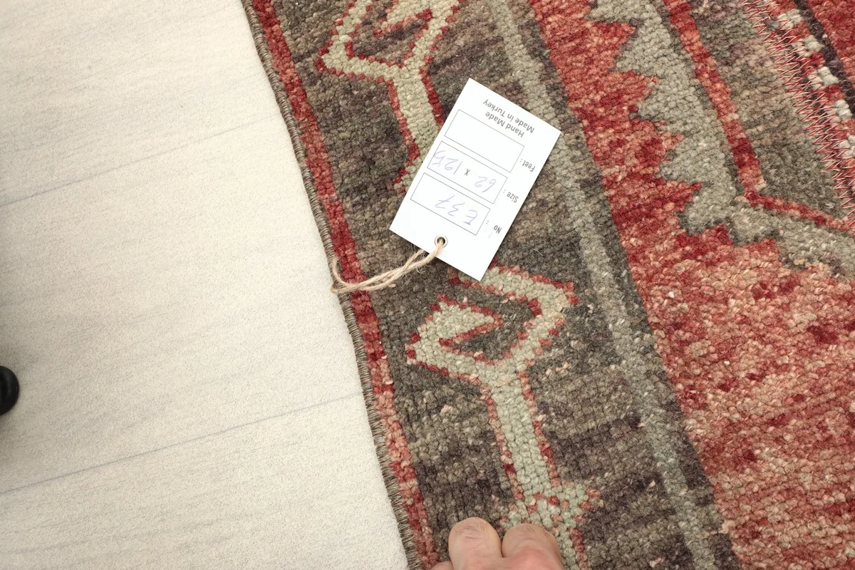 Corner of the rug with a hand and product tag, showing scale and texture