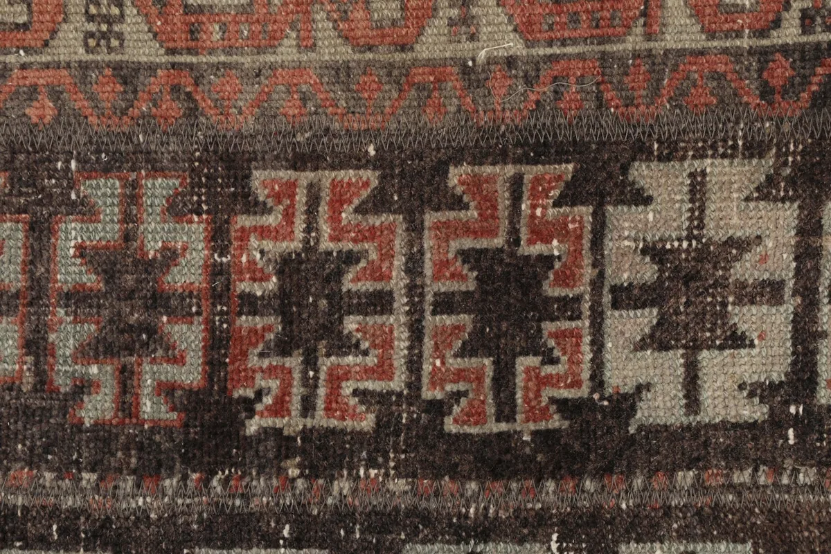 Close-up detail of the intricate geometric patterns in black, rust, and gray wool pile