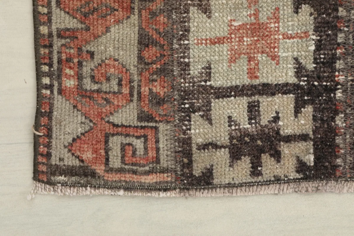 Corner detail of the rug showing the subtle fringe and the border's tribal design