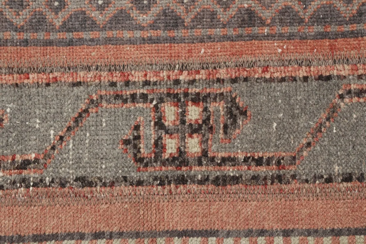 Close-up detail of the gray stripe with tribal motifs and the surrounding rust and brown stripes.