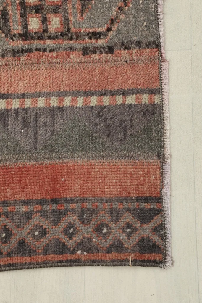 Detailed view of the rug's edge, showing the various color stripes and subtle geometric patterns.