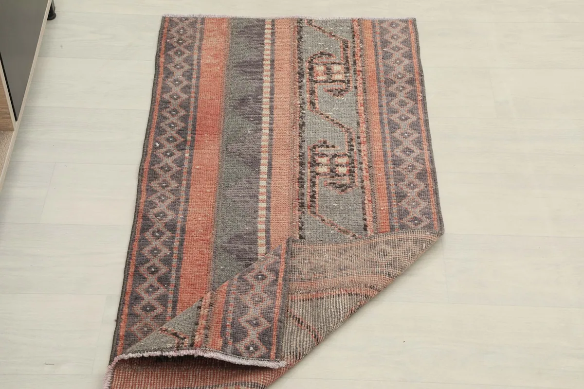 The rug partially folded, showing the flexibility and construction of the vintage piece.