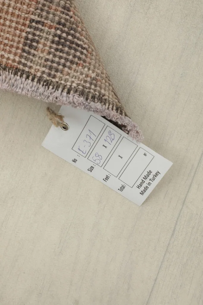 Product tag showing rug dimensions and 'Hand Made in Turkey' on the floor beside the rug.