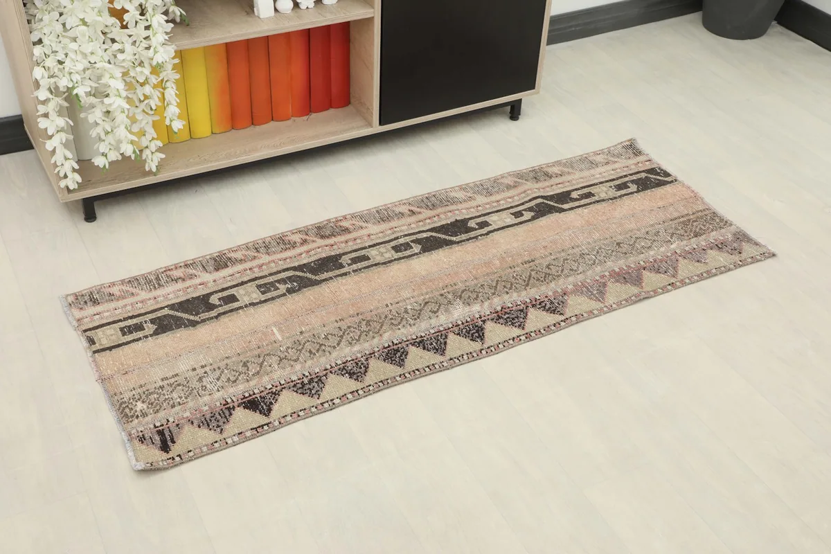 Angled view of the vintage runner rug placed on a light floor, showing its full length and colors in a room setting.