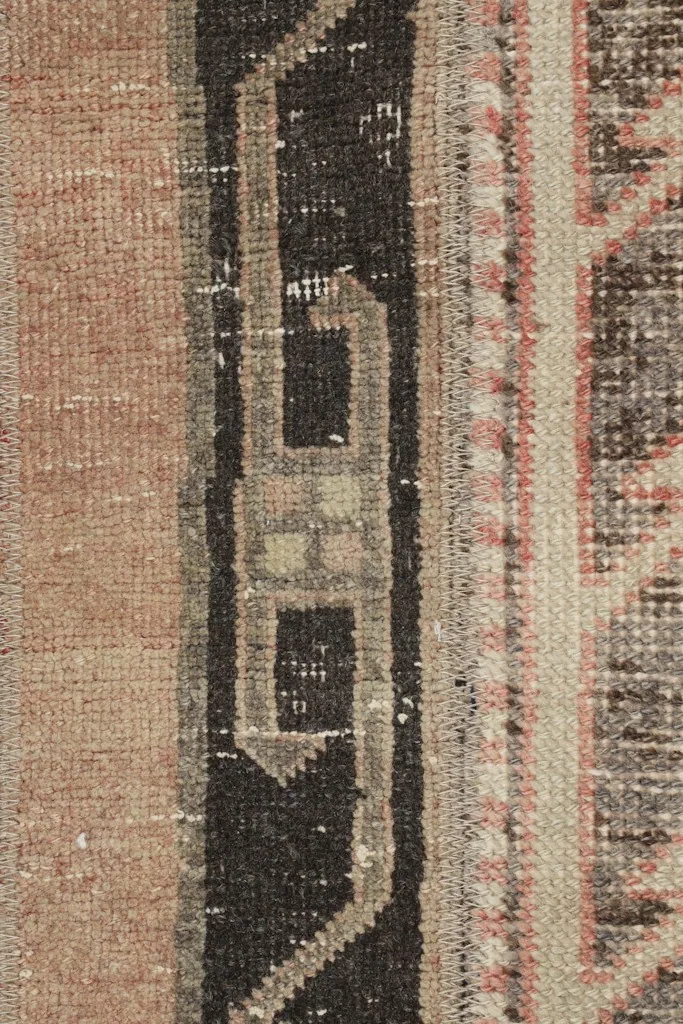 Detailed shot of the central charcoal and beige geometric motif within the striped pattern of the runner rug.