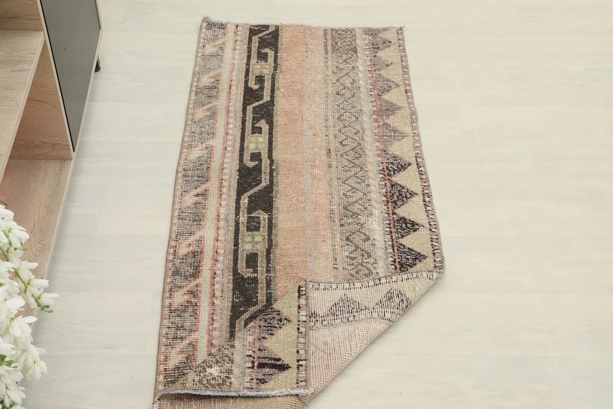 The runner rug with one corner folded back, displaying both the pile side and the foundation.