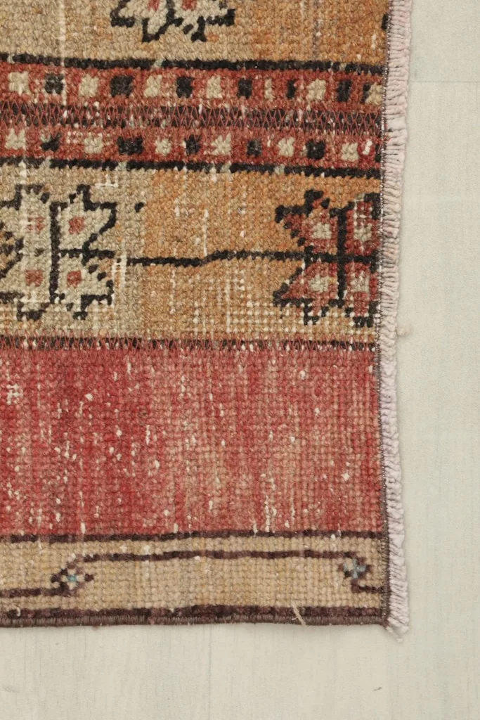 Detail of the rug's edge and subtle border design, showing the short fringe
