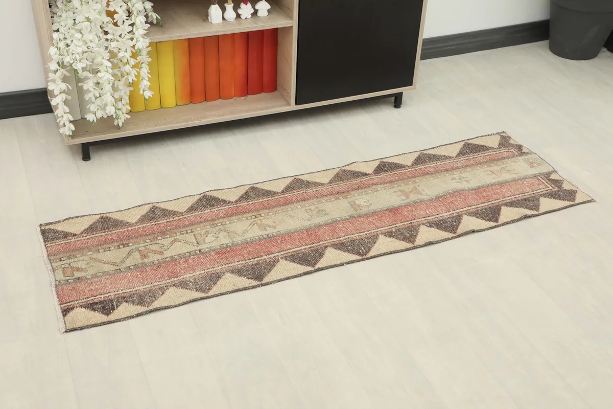 Angled view of the beige and rust runner rug in a room setting, showcasing its length and pattern.