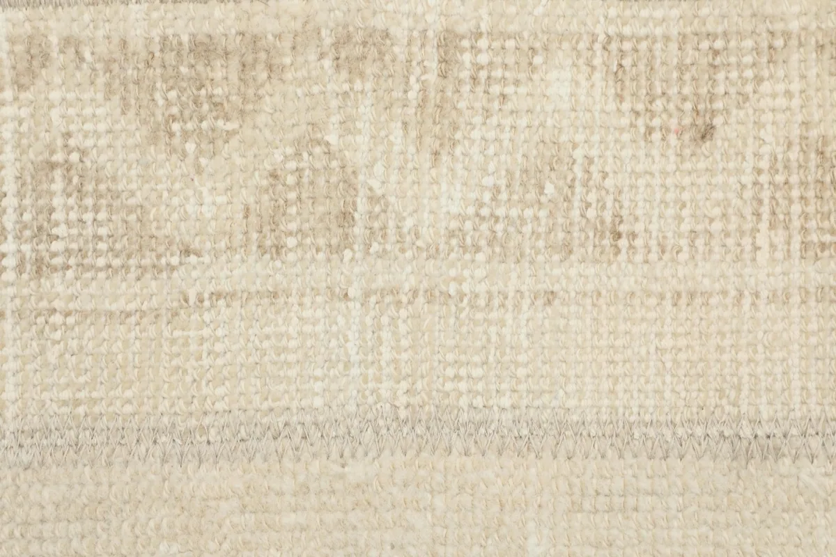 Extreme close-up of the low wool pile, showing the hand-knotted texture and faded geometric motifs.