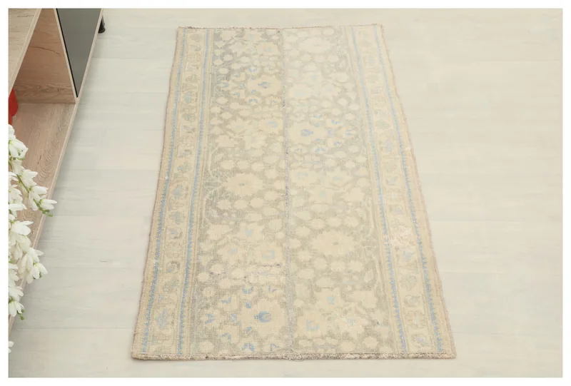 Full top view of the vintage Anatolian rug with a cream and blue floral pattern on a white background.