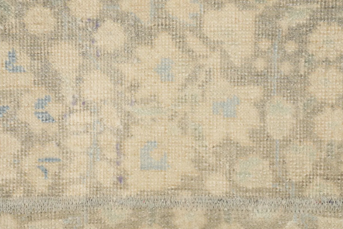 Detailed view of the rug's texture and faded blue and cream floral patterns.