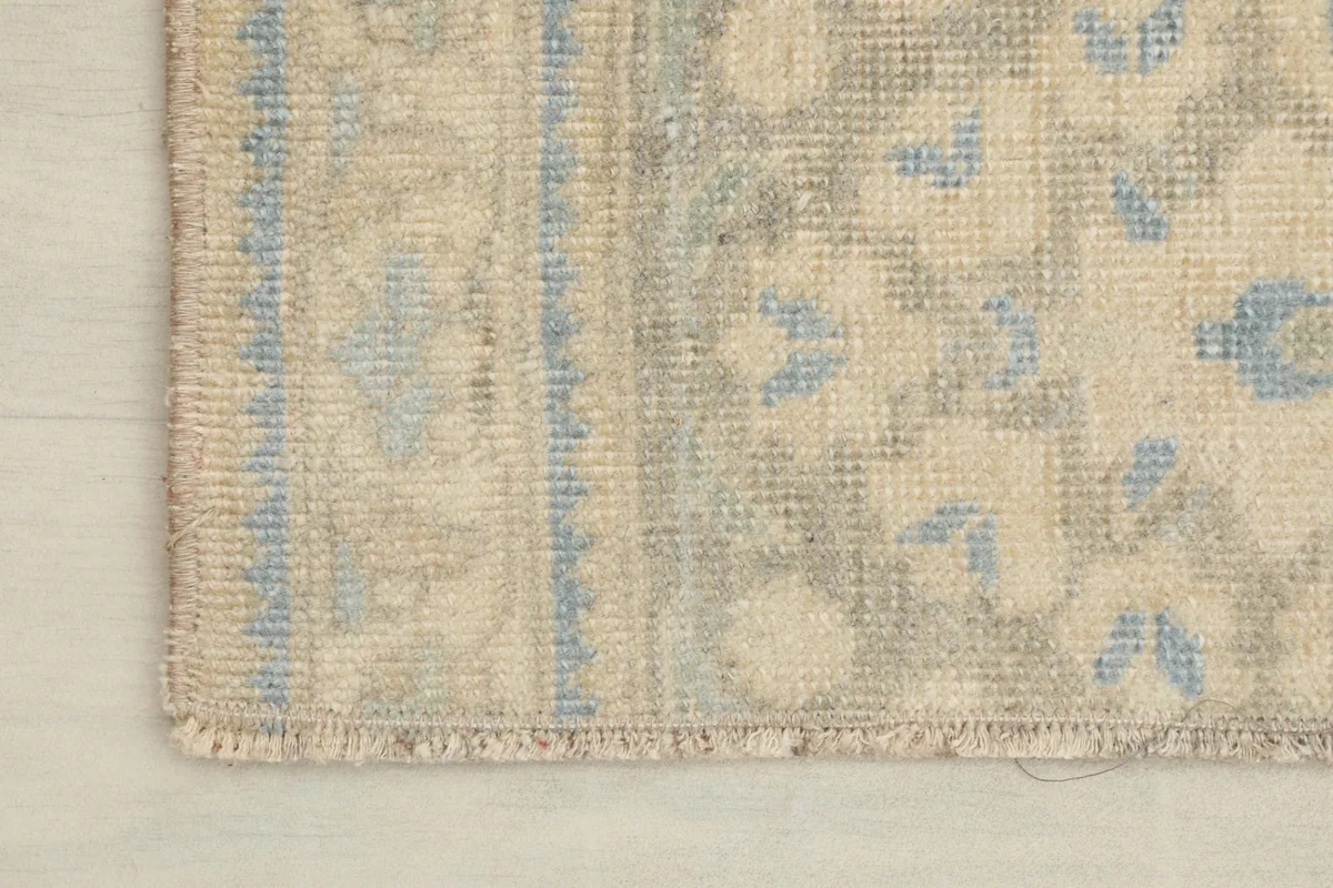 Corner detail showing the rug's border design, fringe, and the hand-knotted wool pile.