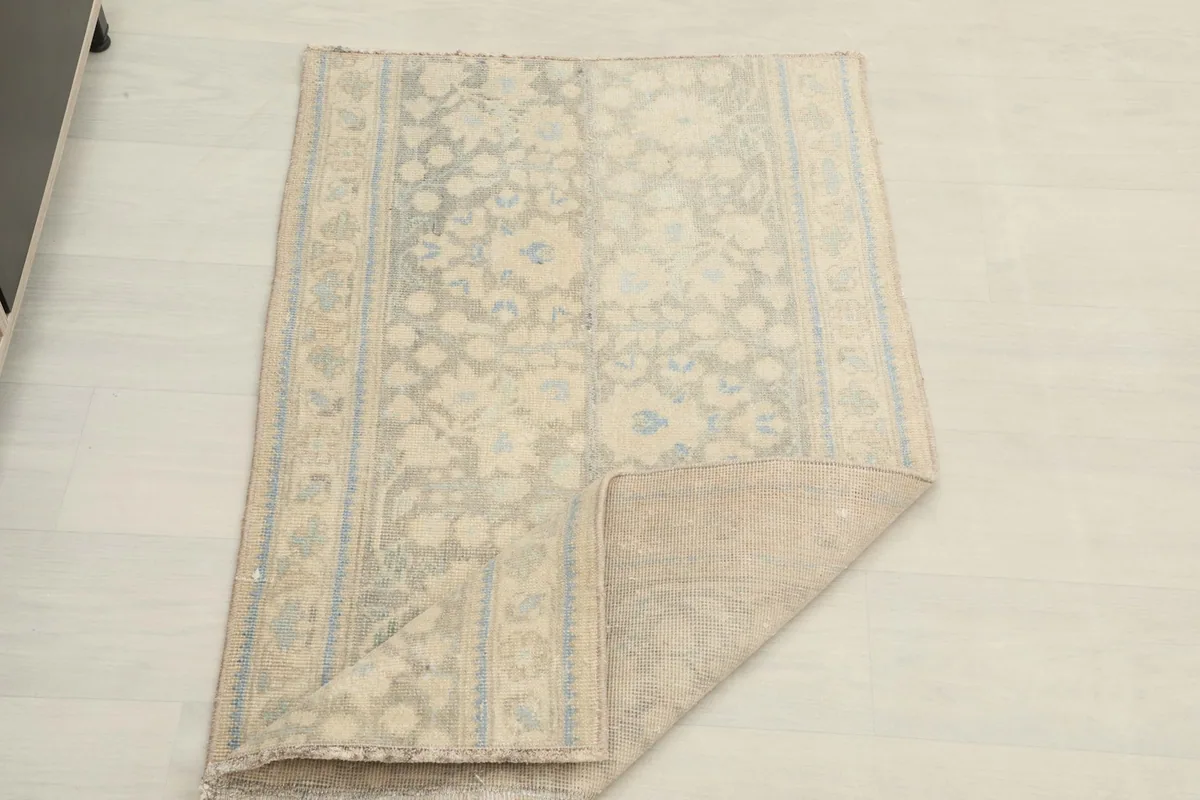 Rug partially folded, revealing the back and front texture and the flexibility of the vintage wool.