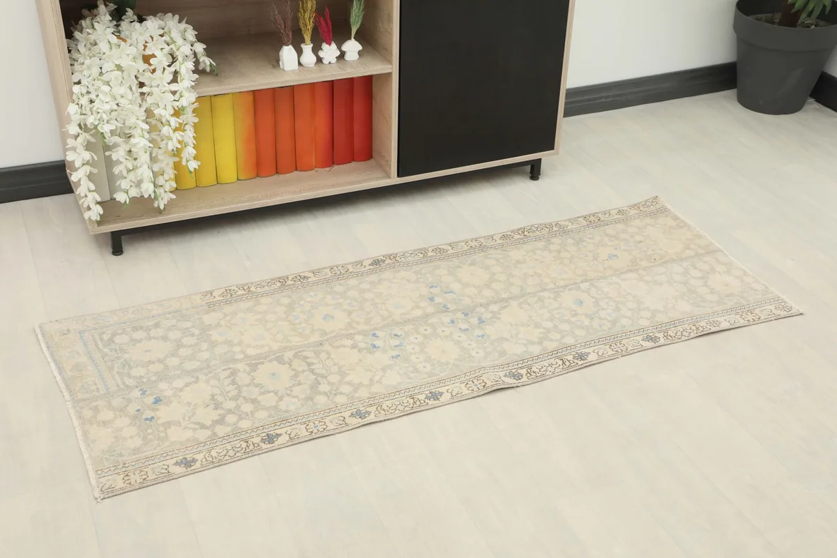 Angled view of the beige runner in a room setting next to a shelf with decor.