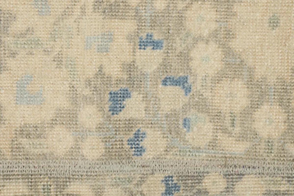 Detailed close-up of the low wool pile and the intricate beige, gray, and blue patterns.