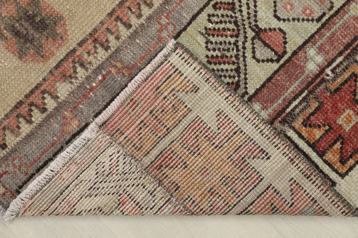 Corner of the rug folded back to reveal the hand-knotted cotton foundation and reverse side.