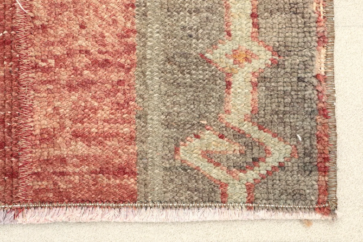 Close-up detail of the hand-knotted wool pile, showing red and gray colors and tribal motifs