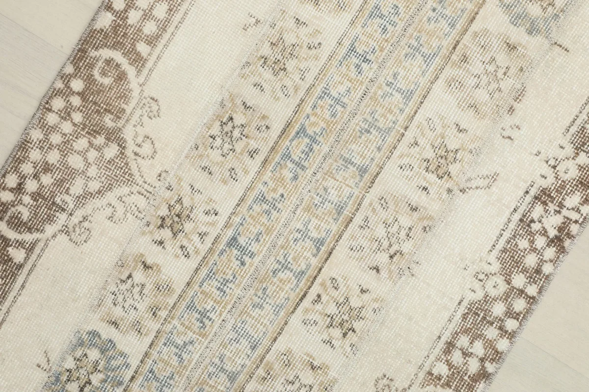 Close-up detail of the runner rug's central design, highlighting the faded blue and brown geometric motifs.