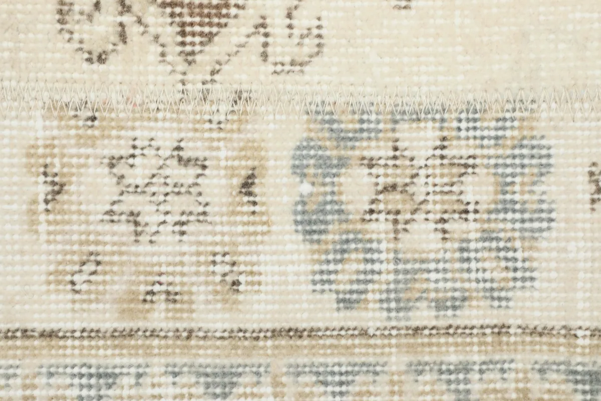 Detailed view of the hand-knotted wool pile, showing the texture and subtle color variations of cream and blue.