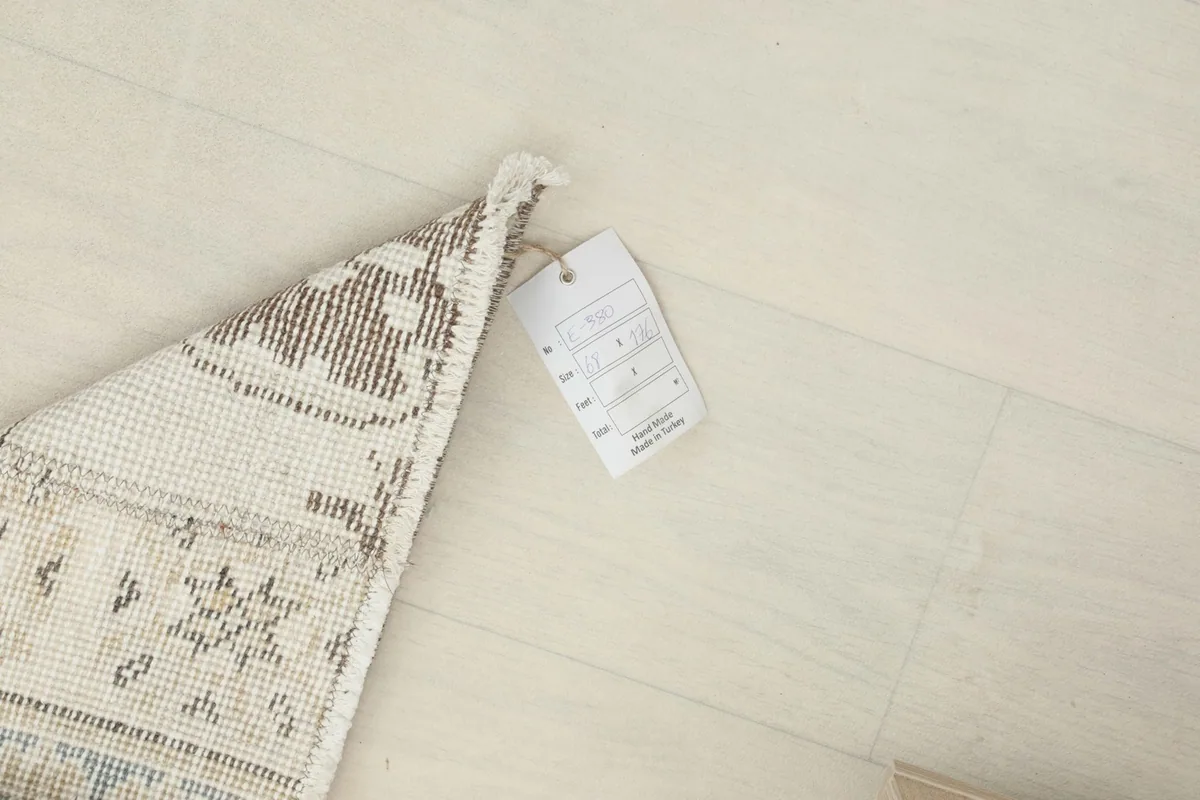 Close-up of the rug's label, showing information about its origin and materials, attached to the corner.