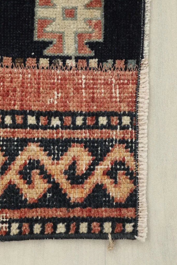 Close-up of the rug's edge, showing the rust border and the short fringe.