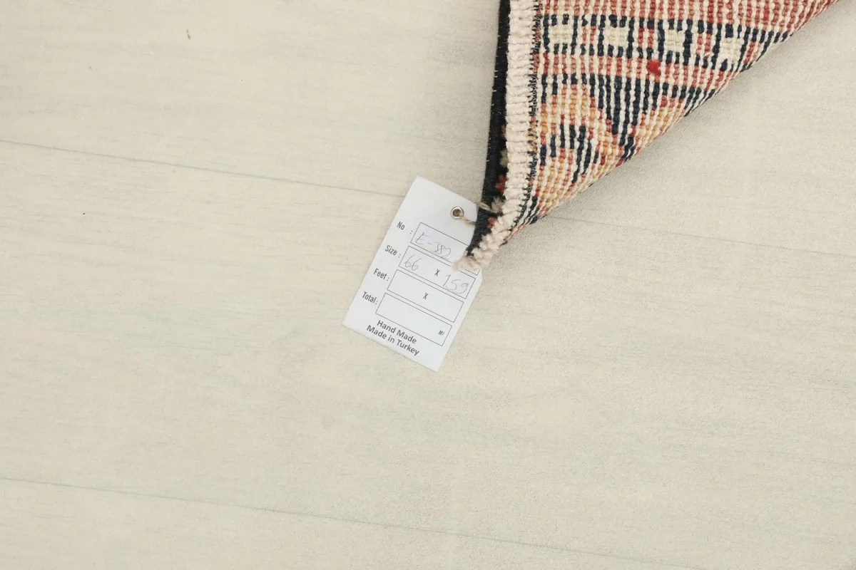 Corner of the rug with a label, showing the hand-knotted detail and backing.