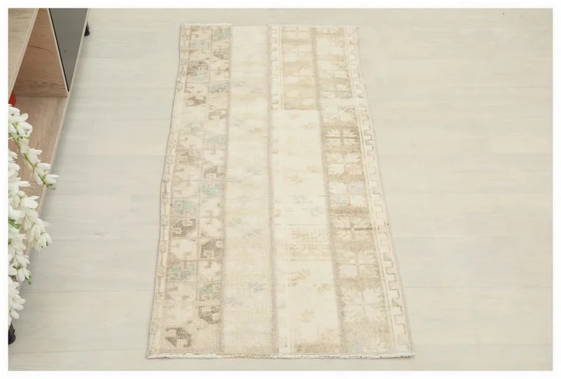 Full top view of an ivory patchwork geometric area rug on a white background