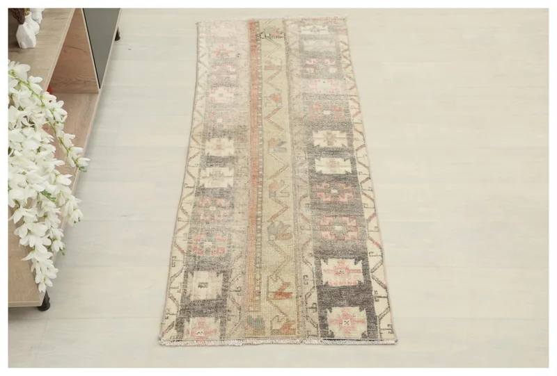Full top view of the 1'10" x 5'0" beige and charcoal vintage runner rug on a white floor.