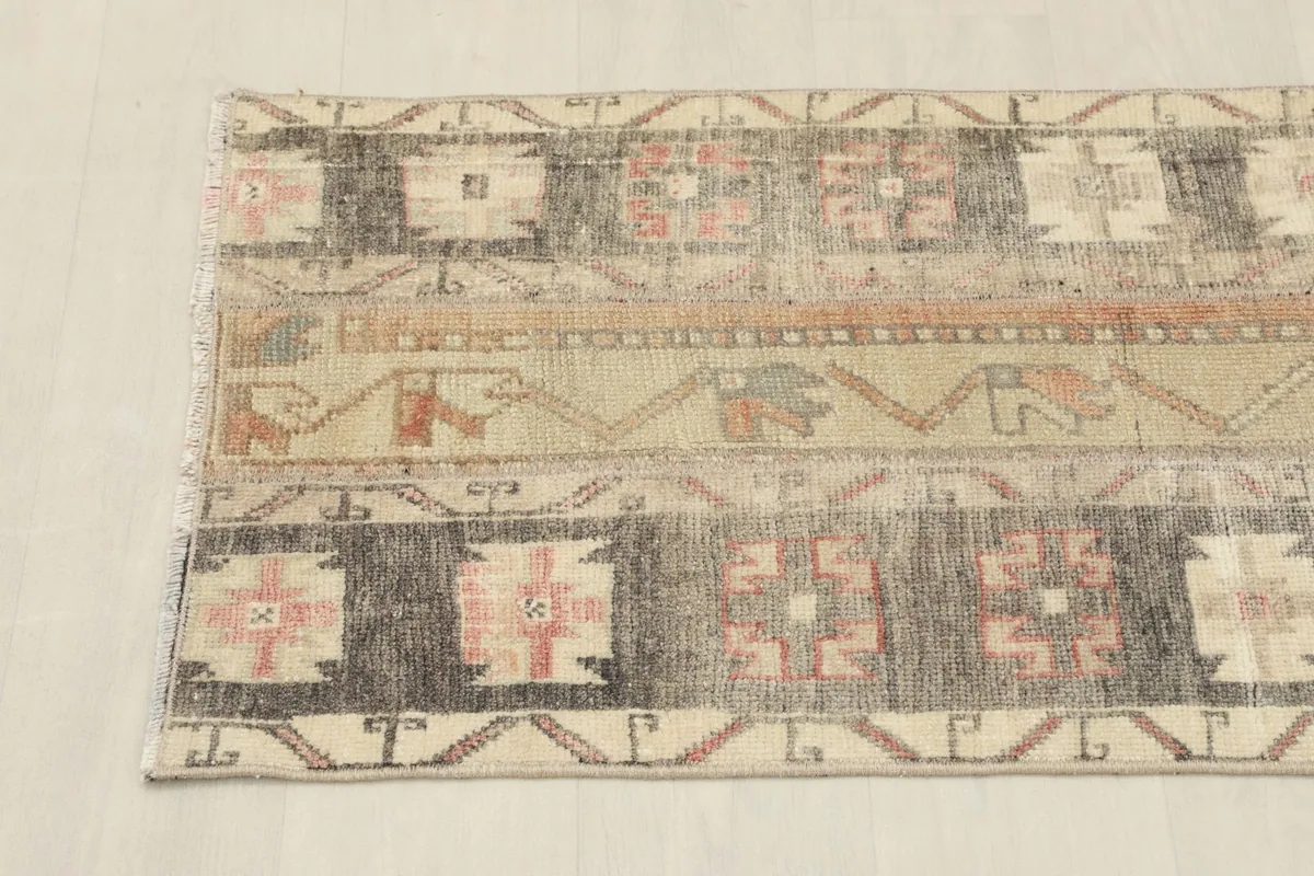 Angled view of one end of the runner, showing the charcoal and beige sections with patterns.