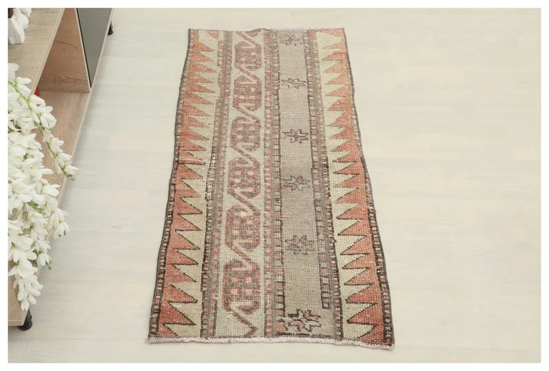 Full top view of the beige and rust tribal geometric runner rug on a light floor.