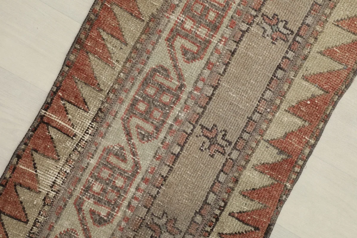 Close-up detail of the rug's hand-knotted tribal geometric motifs and color variations.