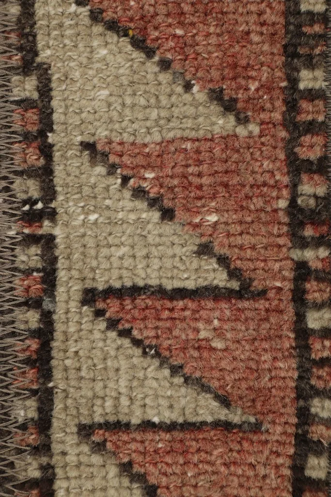 Detailed view of the rust and beige zigzag border and the texture of the wool pile.