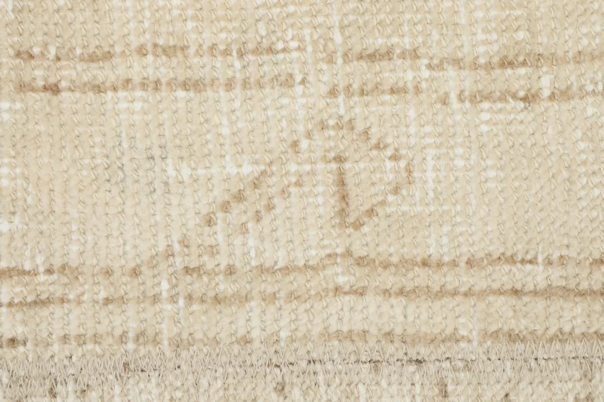 Detailed view of a faded tan tribal symbol within the cream field of the vintage rug