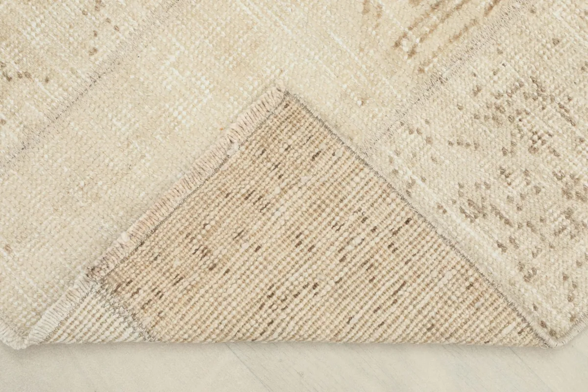 Corner of the rug folded to show the cotton foundation and hand-knotted construction from the back