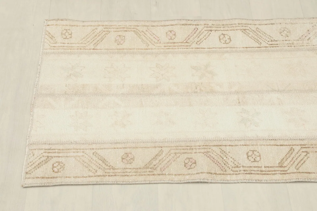 Overhead view showcasing the full length and border patterns of the vintage beige rug