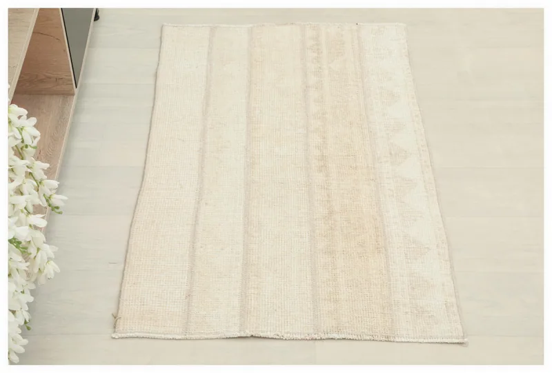 Top view of the beige and ivory striped vintage Anatolian rug on a white floor