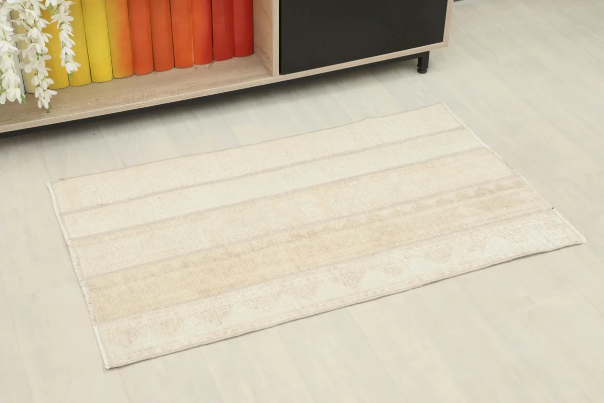 Angled view of the beige rug placed on a light floor in a room setting