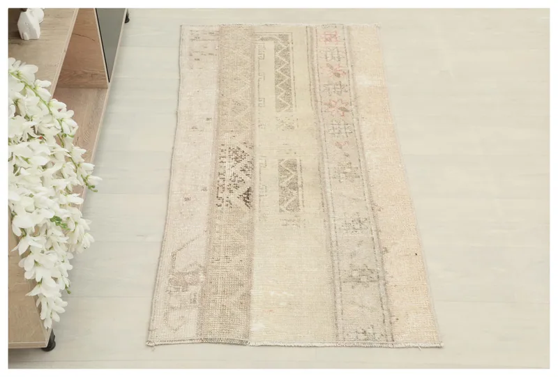 Full top view of a beige patchwork tribal area rug on a white background.