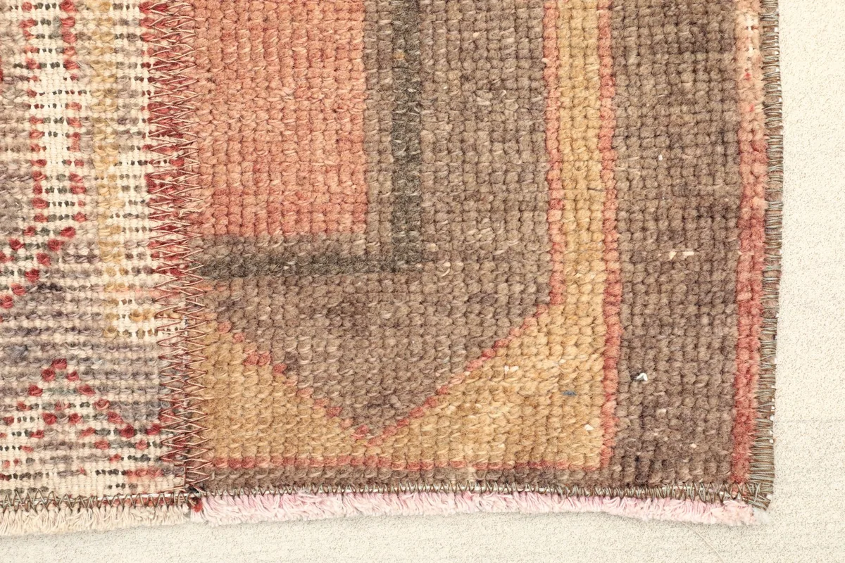 Close-up detail of one end of the rug, showing the wool pile and varied textile textures.