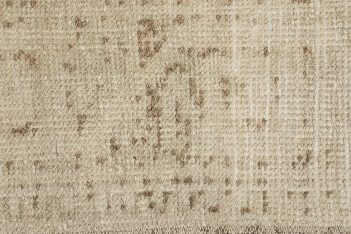 Detailed view of the faded geometric patterns and low pile texture on the beige rug