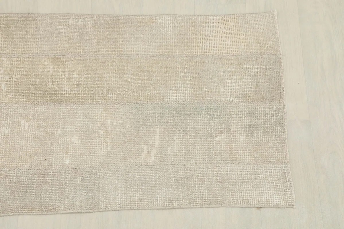 Overhead shot of one end of the 2x5 area rug, showing the faded geometric lines and soft colors.