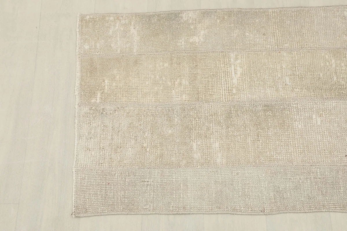 Overhead shot of the other end of the vintage rug, emphasizing the overall muted beige and cream tones.