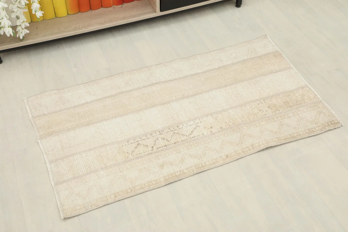 Angled view of the vintage wool rug, showing its striped pattern and soft colors.