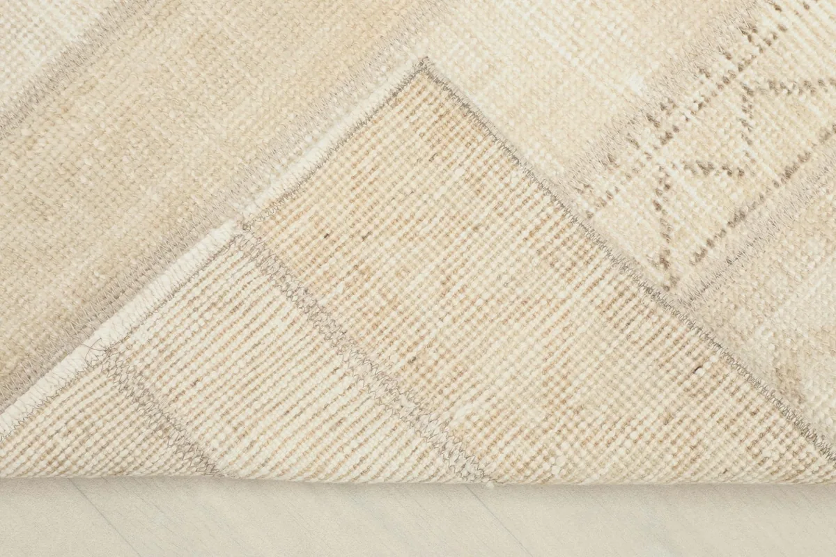 Corner of the rug folded back to reveal the back structure and foundation.