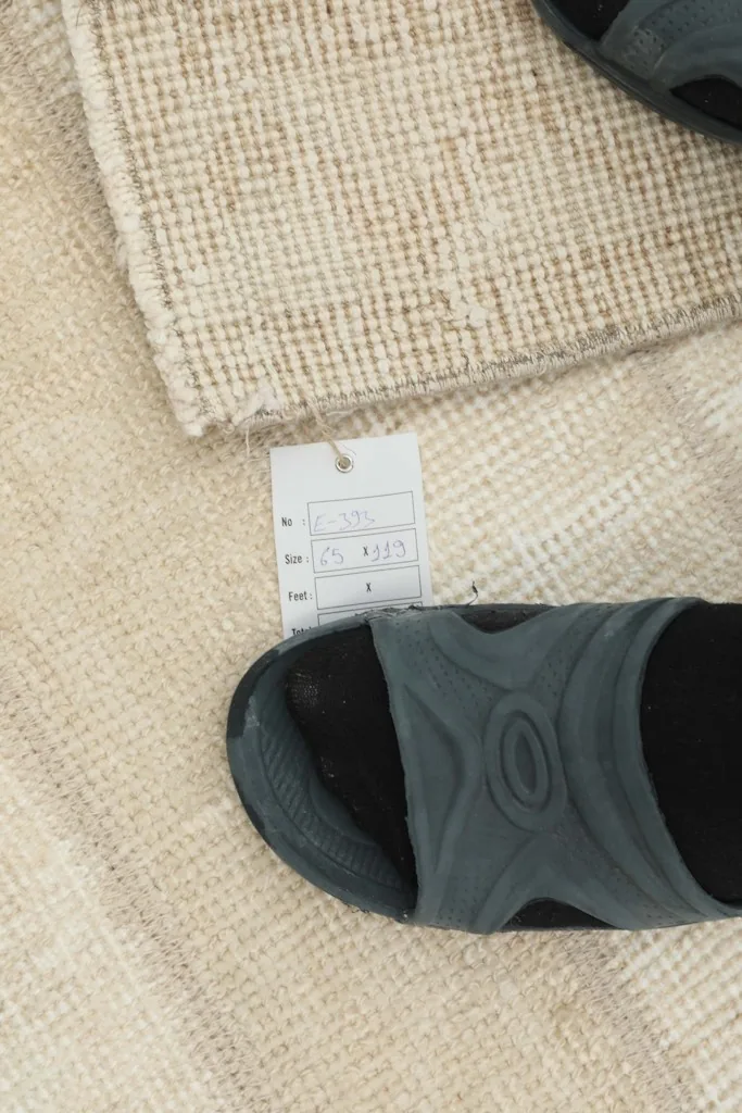 A close-up of the rug's texture and a sizing tag, with a shoe for scale.
