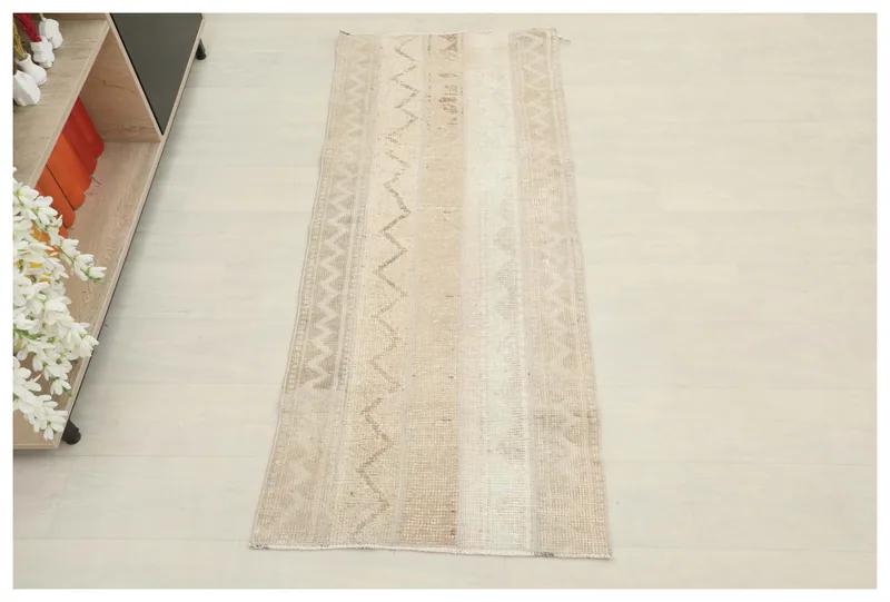 Full overhead view of the beige striped tribal runner rug on a white floor